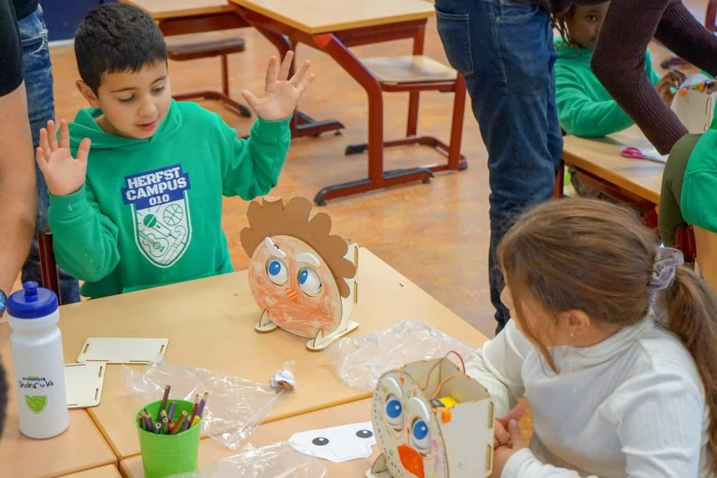 een leerling met een kleurrijk knutselwerkje van karton, papier en elektronica